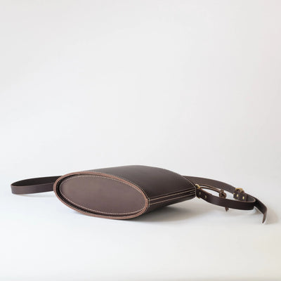 Brown leather bag with a strap on a white background