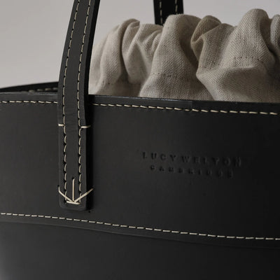 Black leather bag with 'Lucy Williams' branding and beige fabric interior.