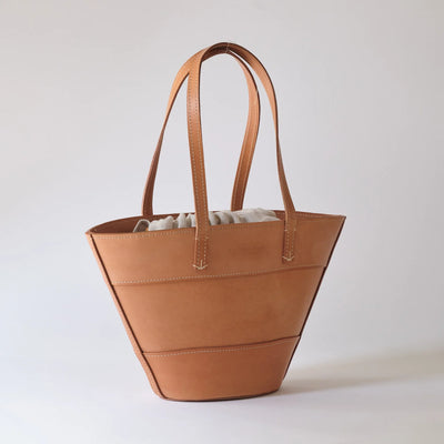 Brown leather tote bag on a light gray background