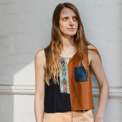 Woman wearing a sleeveless top with a colorful pattern against a gray wall