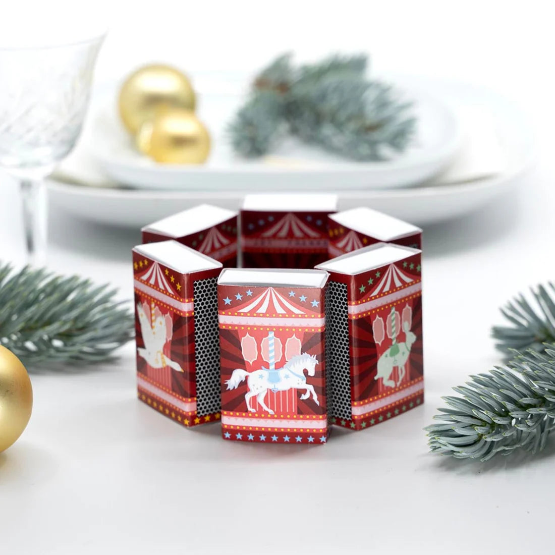 Decorative candle holder with carousel design on a white surface with Christmas decorations.