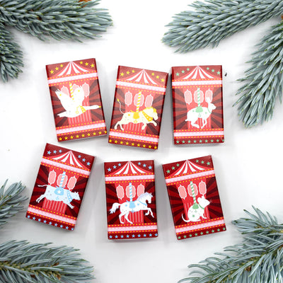 Six small red packages with carousel designs on a white background with pine branches.