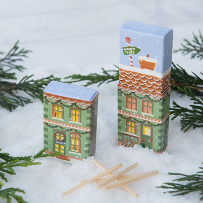 Two small building-shaped boxes with Christmas designs on a snowy background