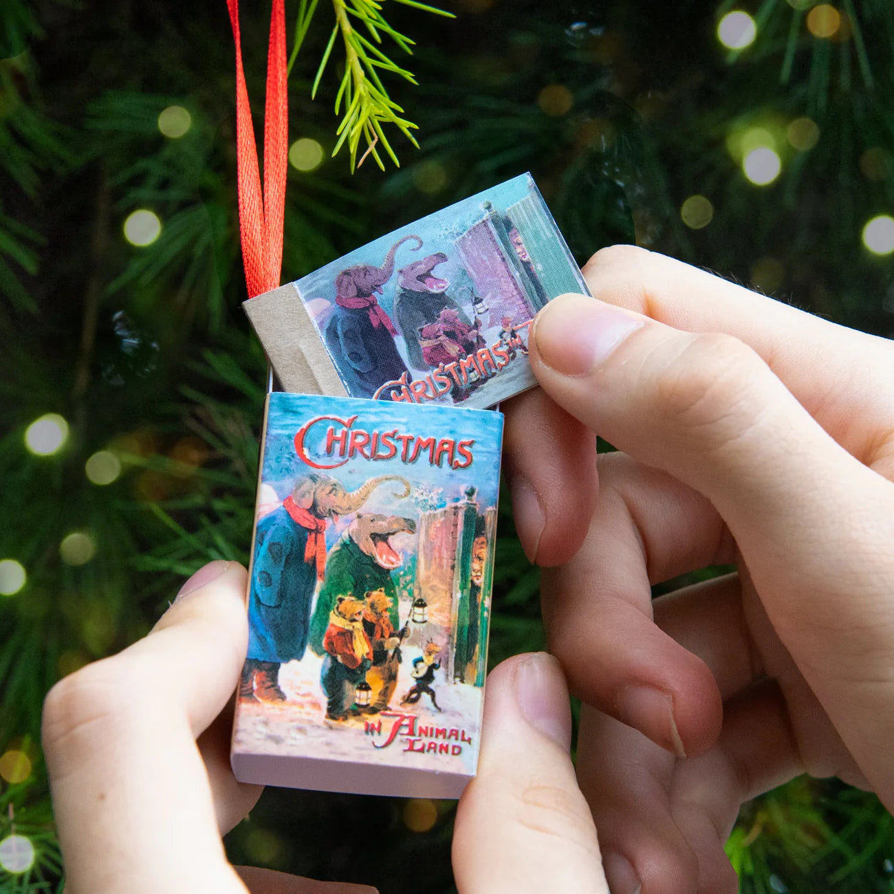 VHS tape Christmas ornament held by hands with a blurred Christmas tree background