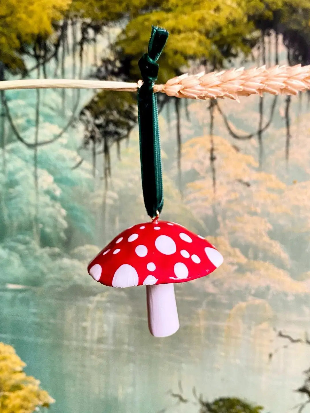 Mushroom-shaped ornament hanging from a branch with a blurred natural background