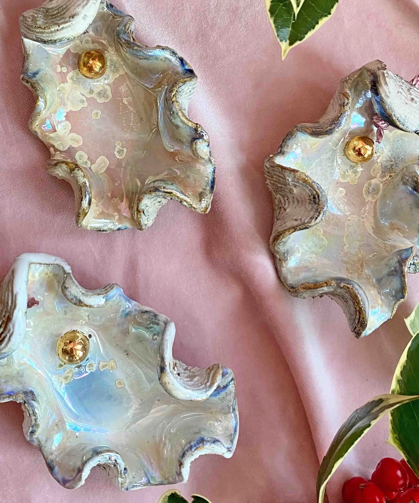 Shell-shaped earrings with gold centers on a pink background