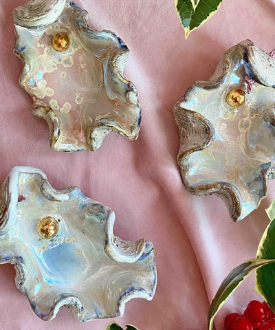 Shell-shaped earrings with gold centers on a pink background