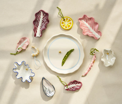 Decorative ceramic items shaped like vegetables and leaves on a light background