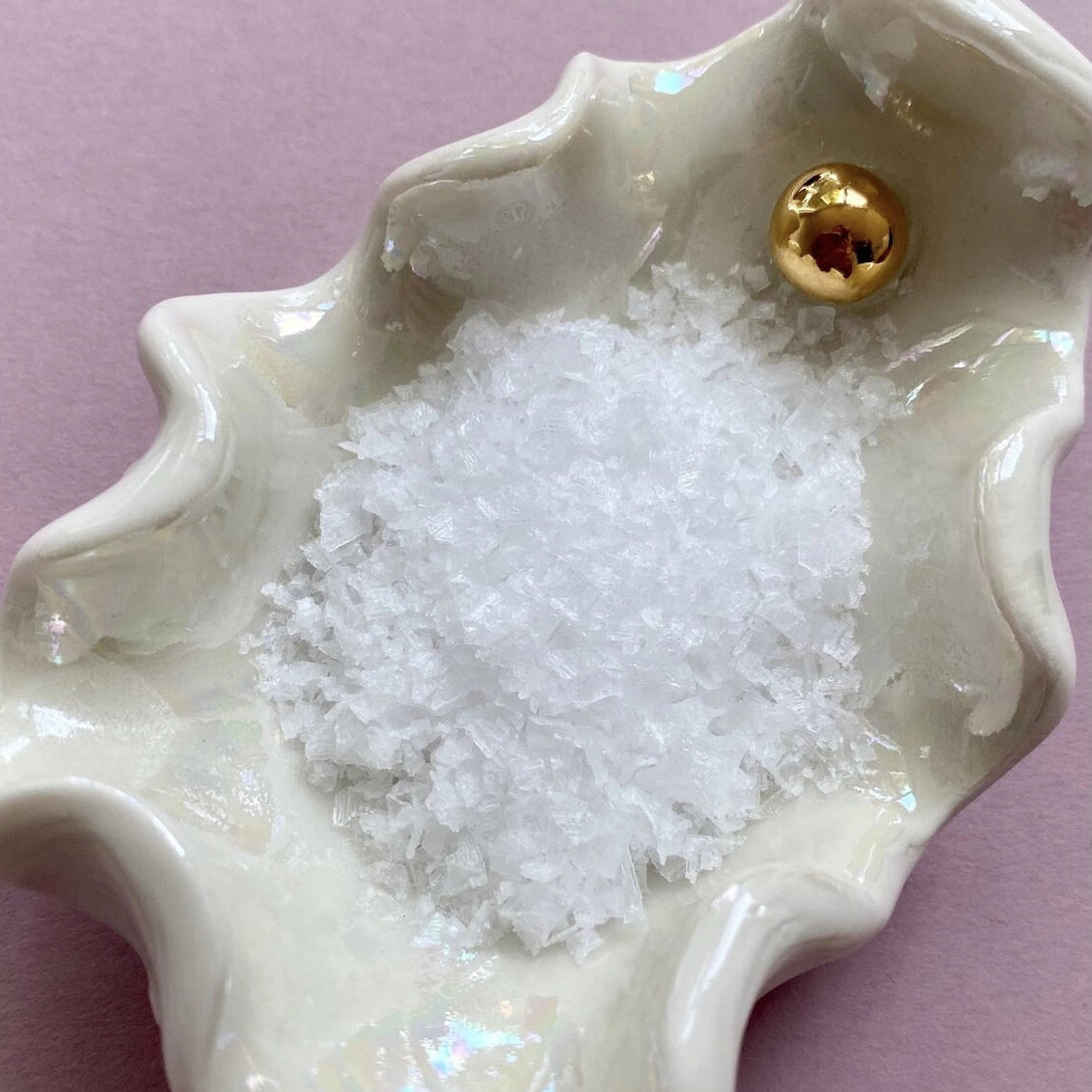 White ceramic dish with a gold accent on a pink background