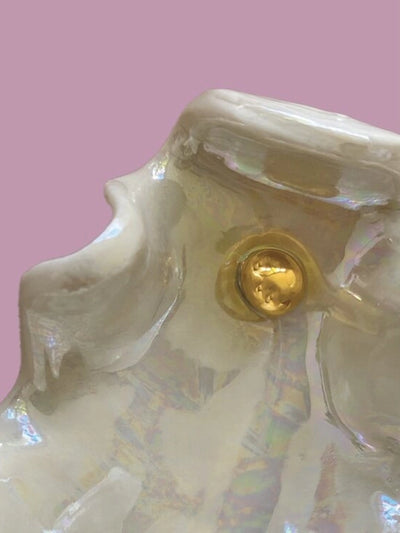 Close-up of a ceramic dog figurine with a gold button on a pink background