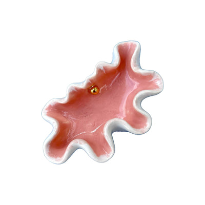 Pink ceramic octopus with a gold eye on a white background