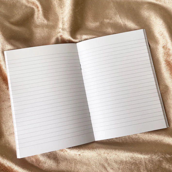 Open notebook with lined pages on a beige fabric background