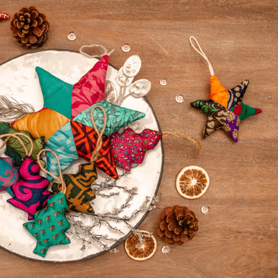Colorful fabric ornaments on a wooden surface with pine cones and dried oranges.