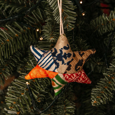 Star-shaped fabric ornament with multicolor patterns hanging on a Christmas tree.
