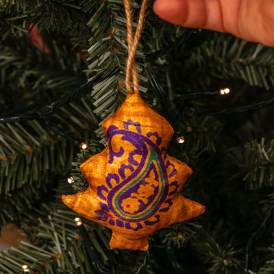 Star-shaped orange ornament with purple design on a Christmas tree