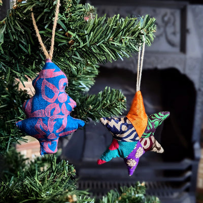 Colorful star-shaped fabric ornaments hanging on a Christmas tree.