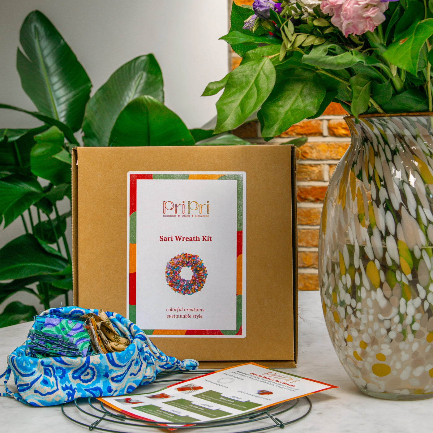 Sari wreath kit with materials and instructions on a table with plants in the background