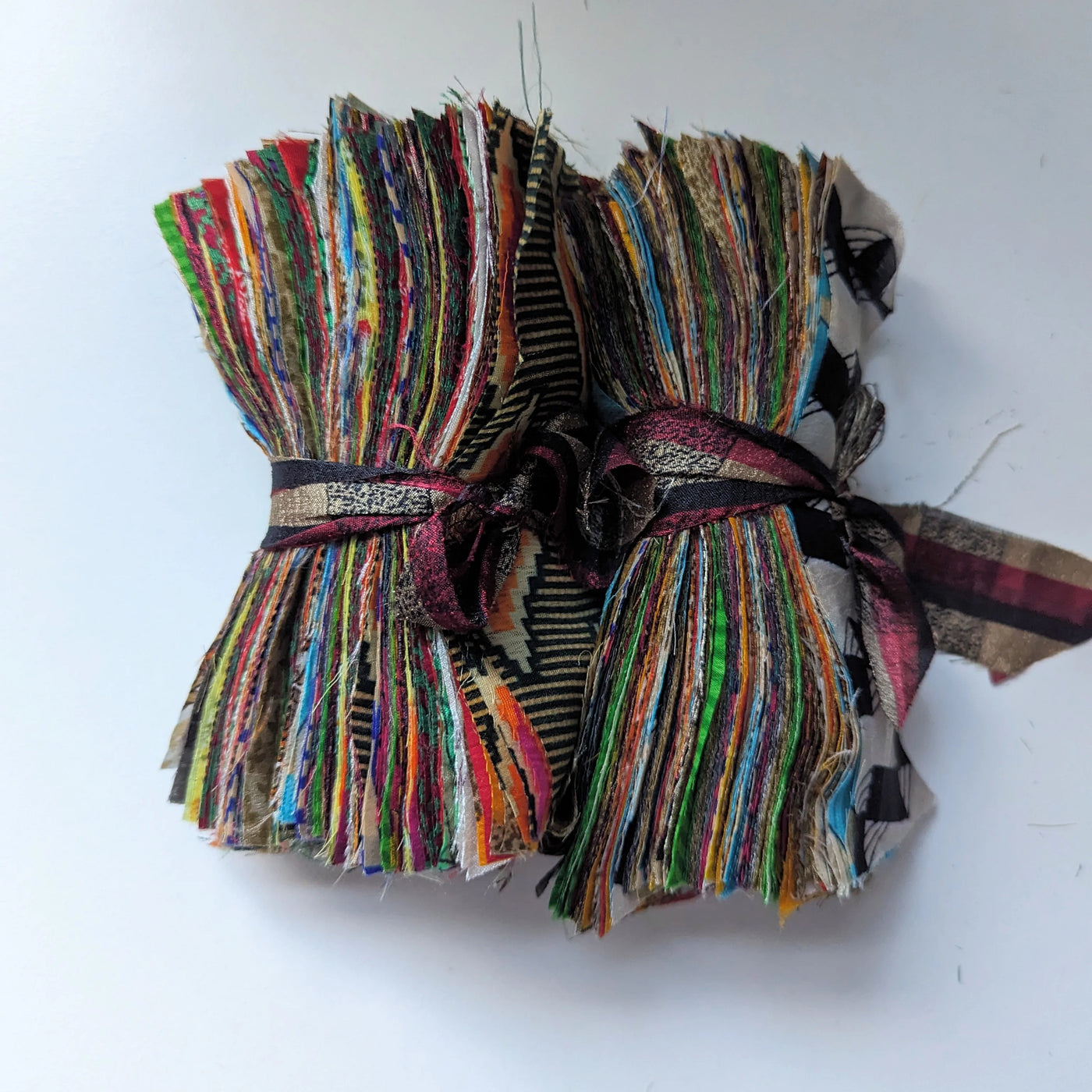 Bunch of colorful fabric strips tied together on a white background