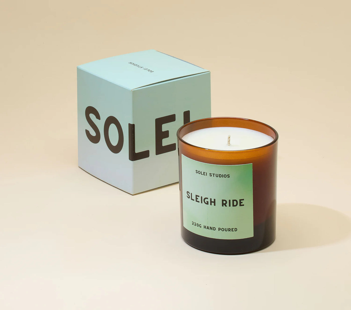 Solei Studios candle labeled 'Sleigh Ride' with a matching box on a beige background