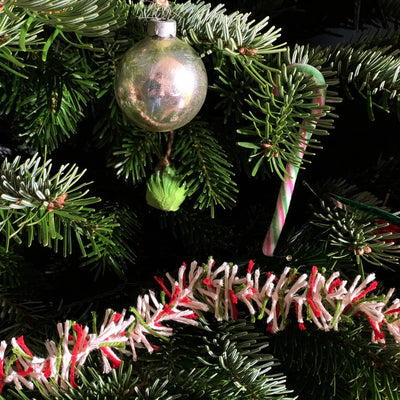 Close-up of a Christmas tree with a ornament and candy cane against a dark background