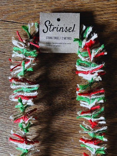 Decorative string tinsel with a 'Strinsiel' tag on a wooden surface