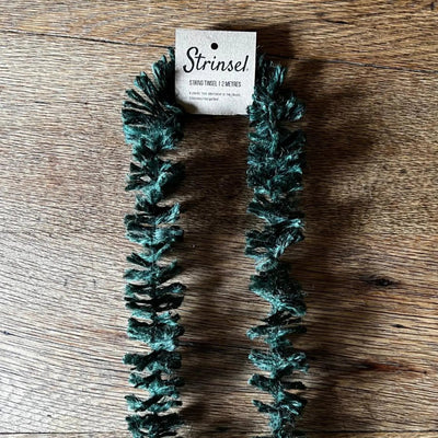 Teal dog toy with packaging labeled 'Strinse' on a wooden surface