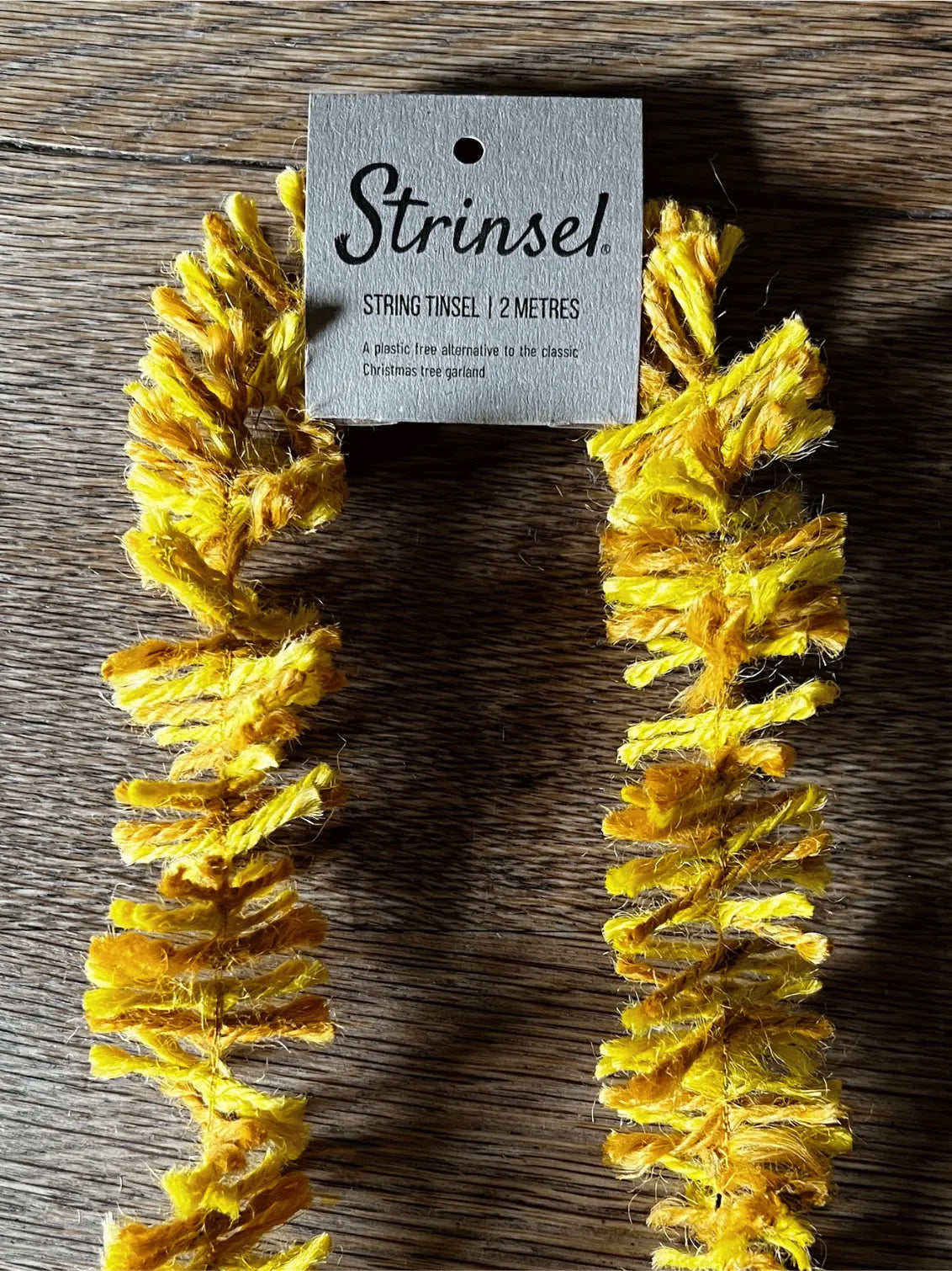 Yellow string tinsel with a 'Strinzel' tag on a wooden surface