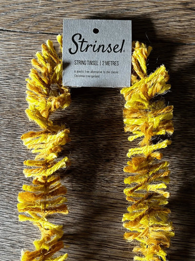 Yellow string tinsel with a 'Strinzel' tag on a wooden surface