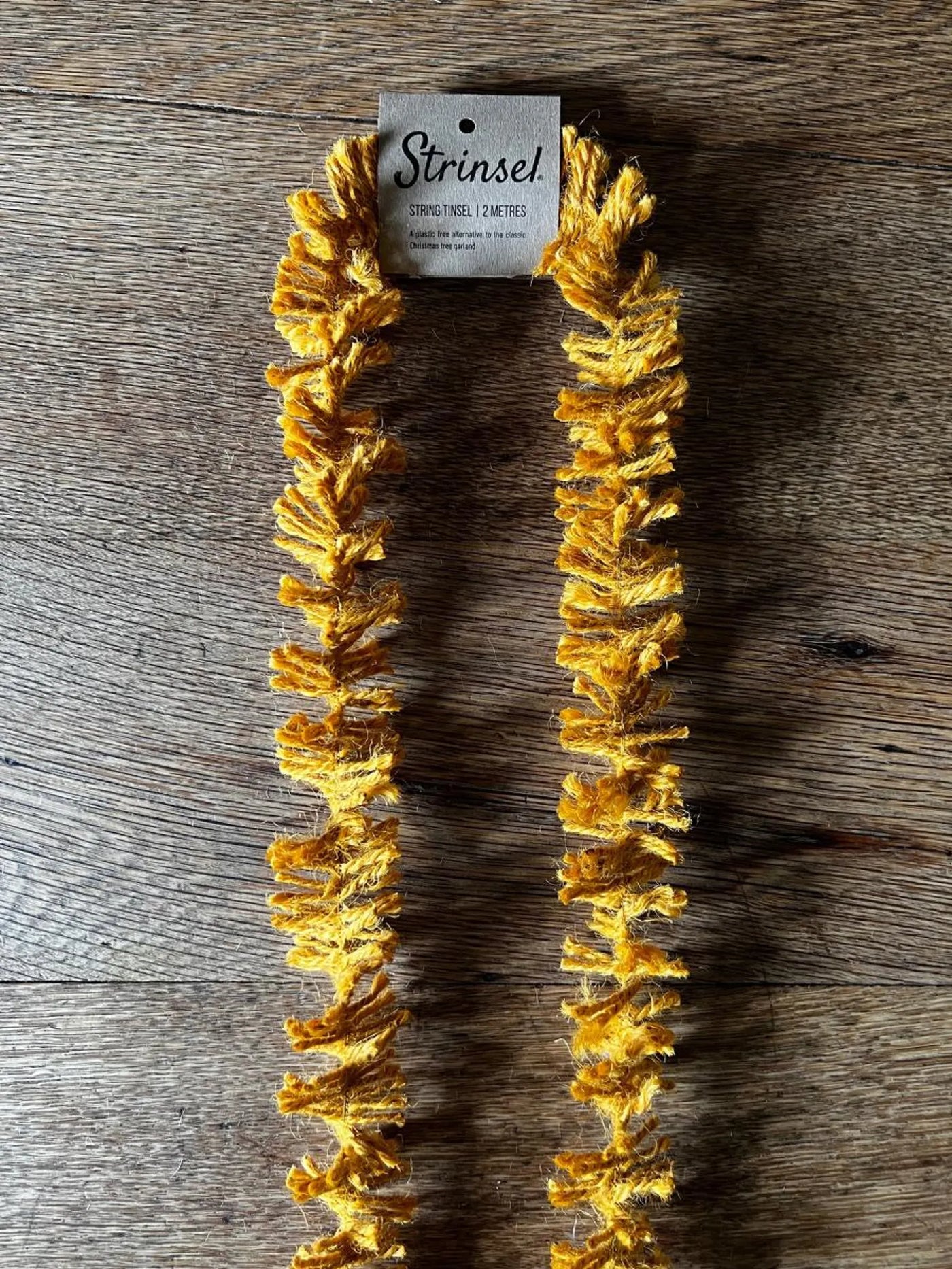 Gold dog toy with 'Strinis' branding on a wooden surface
