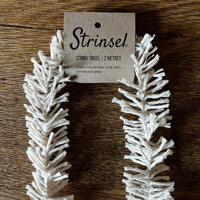 White string tinsel with a 'Strinse!' label on a wooden surface