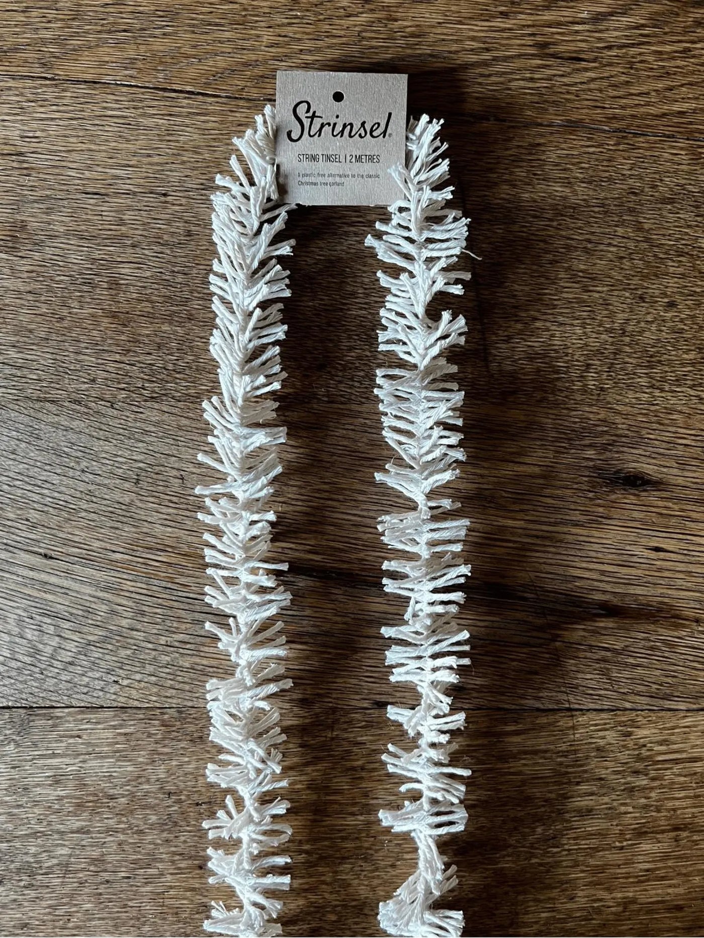 White string of lights on a wooden surface with a 'Strinzel' label.