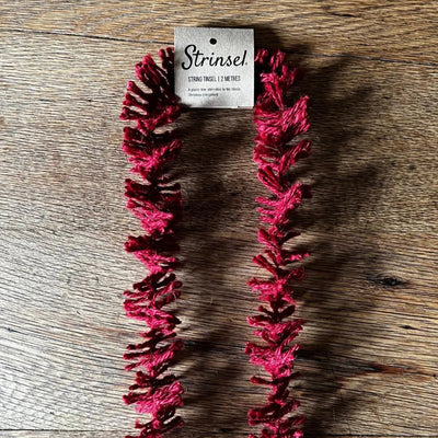 Red string necklace on a wooden surface with 'Strinsei' packaging.