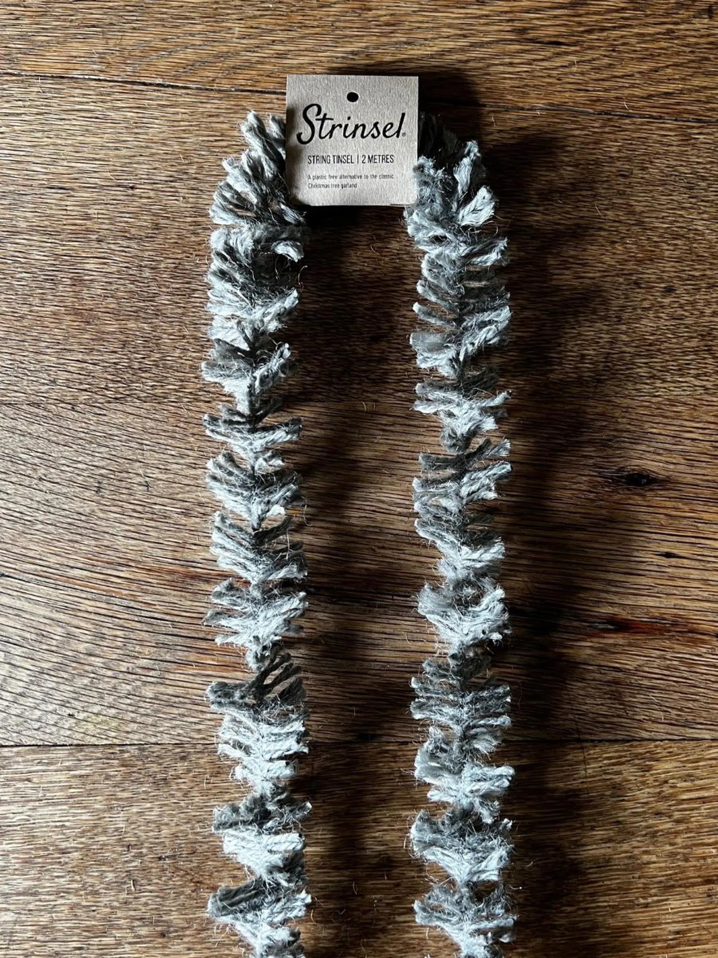 Faux fur scarf with snowflake pattern on a wooden surface, branded 'Strinsel'.