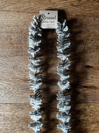 Faux fur scarf with snowflake pattern on a wooden surface, branded 'Strinsel'.