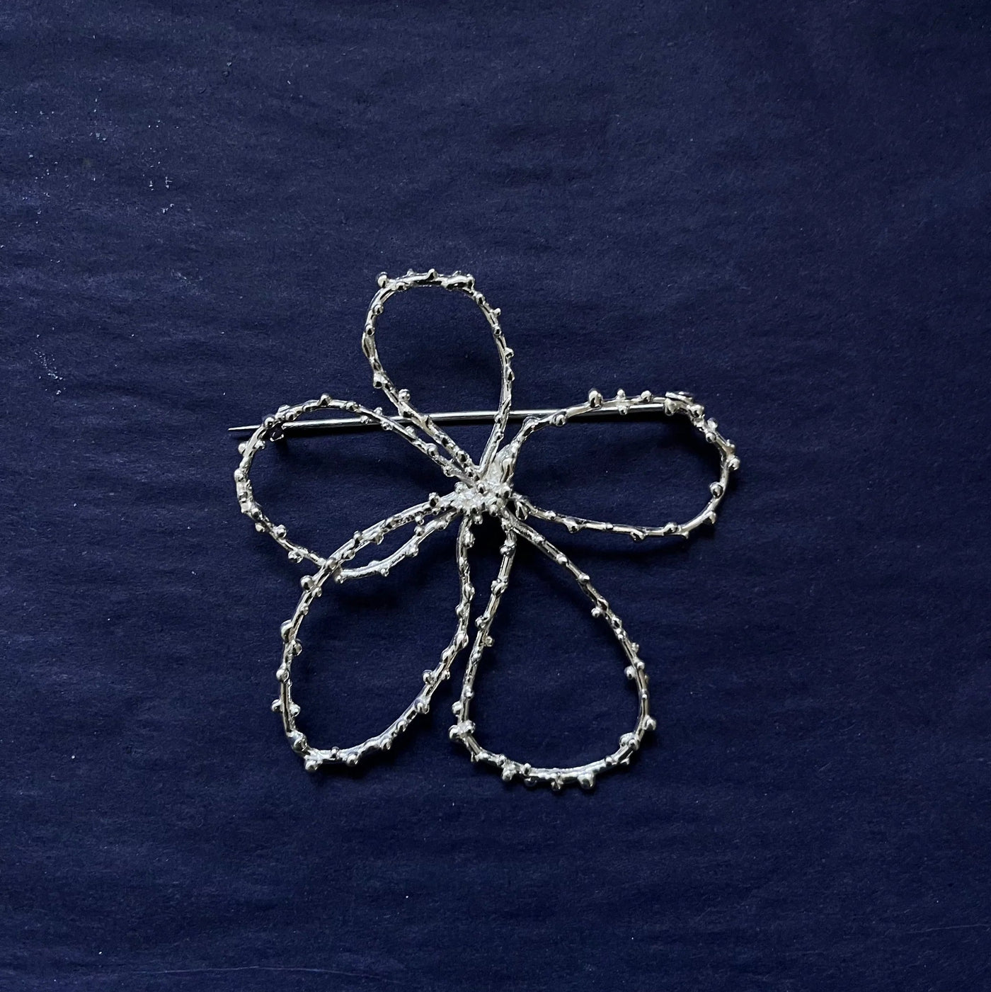 Silver floral embroidery on a dark blue fabric background