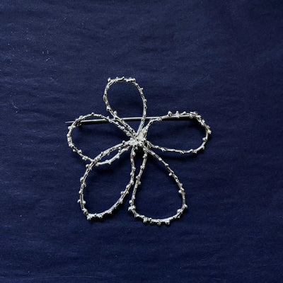 Silver floral embroidery on a dark blue fabric background