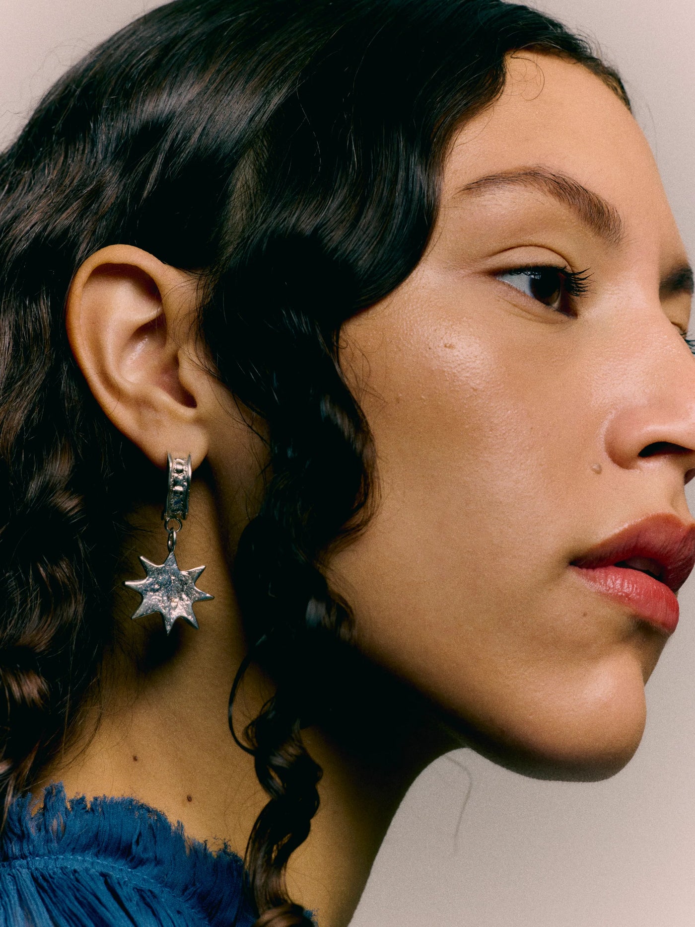 Close-up of a person wearing a star-shaped earring with a neutral background