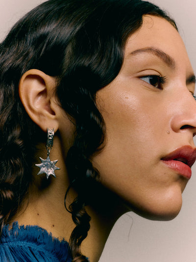 Close-up of a person wearing a star-shaped earring with a neutral background