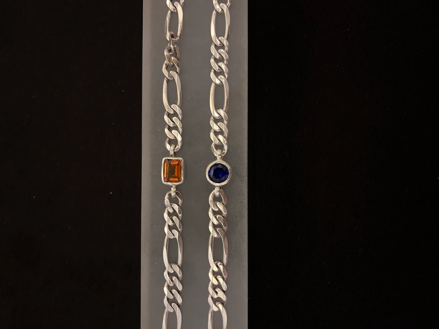 Silver chain bracelet with gemstone accents on a black background
