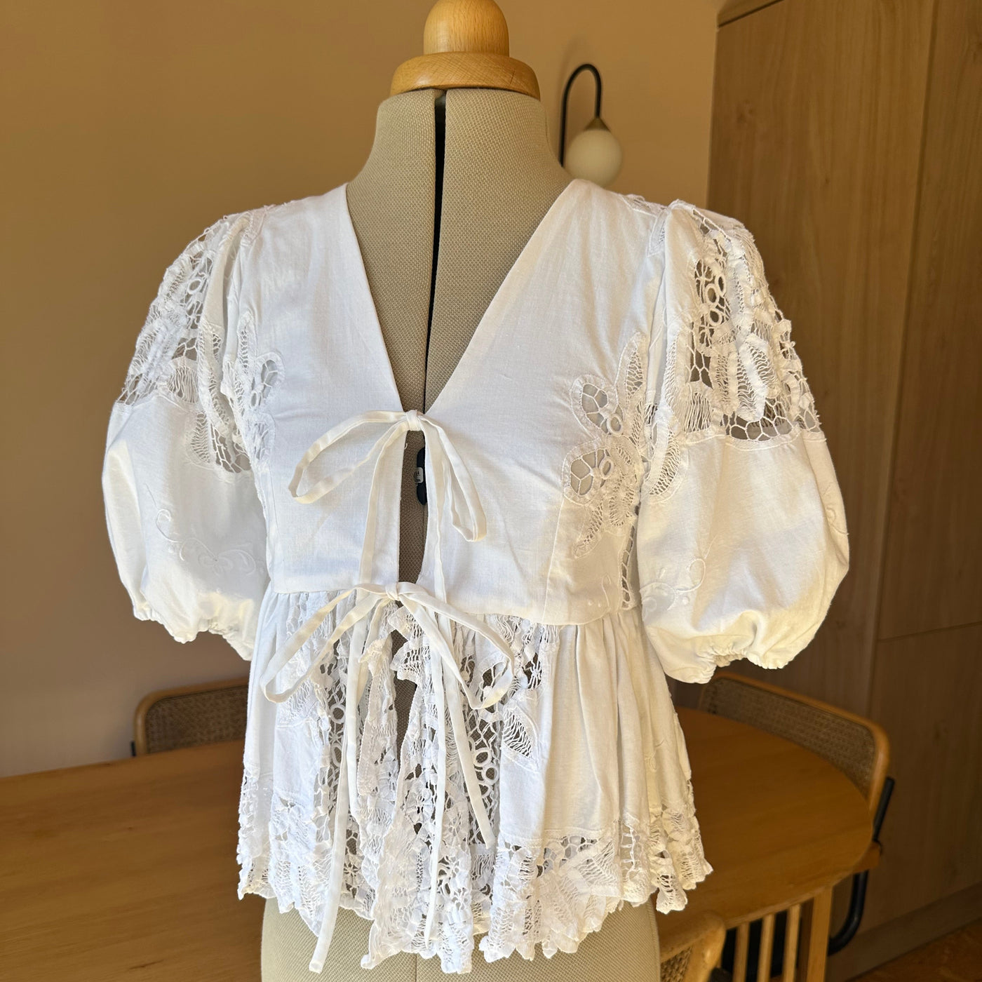 White lace top on a mannequin against a neutral background