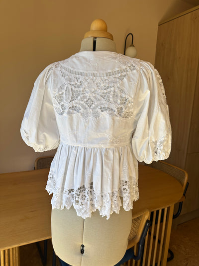 White lace top on a mannequin against a neutral background