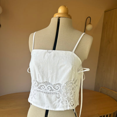 White lace top on a mannequin against a neutral background