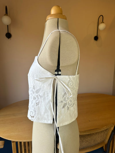 Mannequin wearing a beige lace top with a plain background