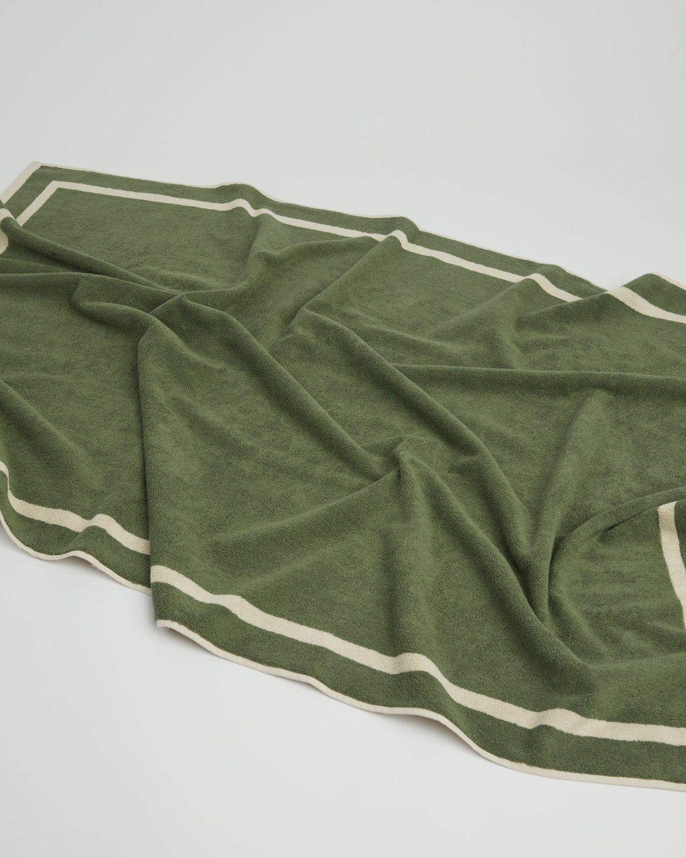 Green towel with white stripes on a light gray background