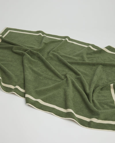 Green towel with white stripes on a light gray background
