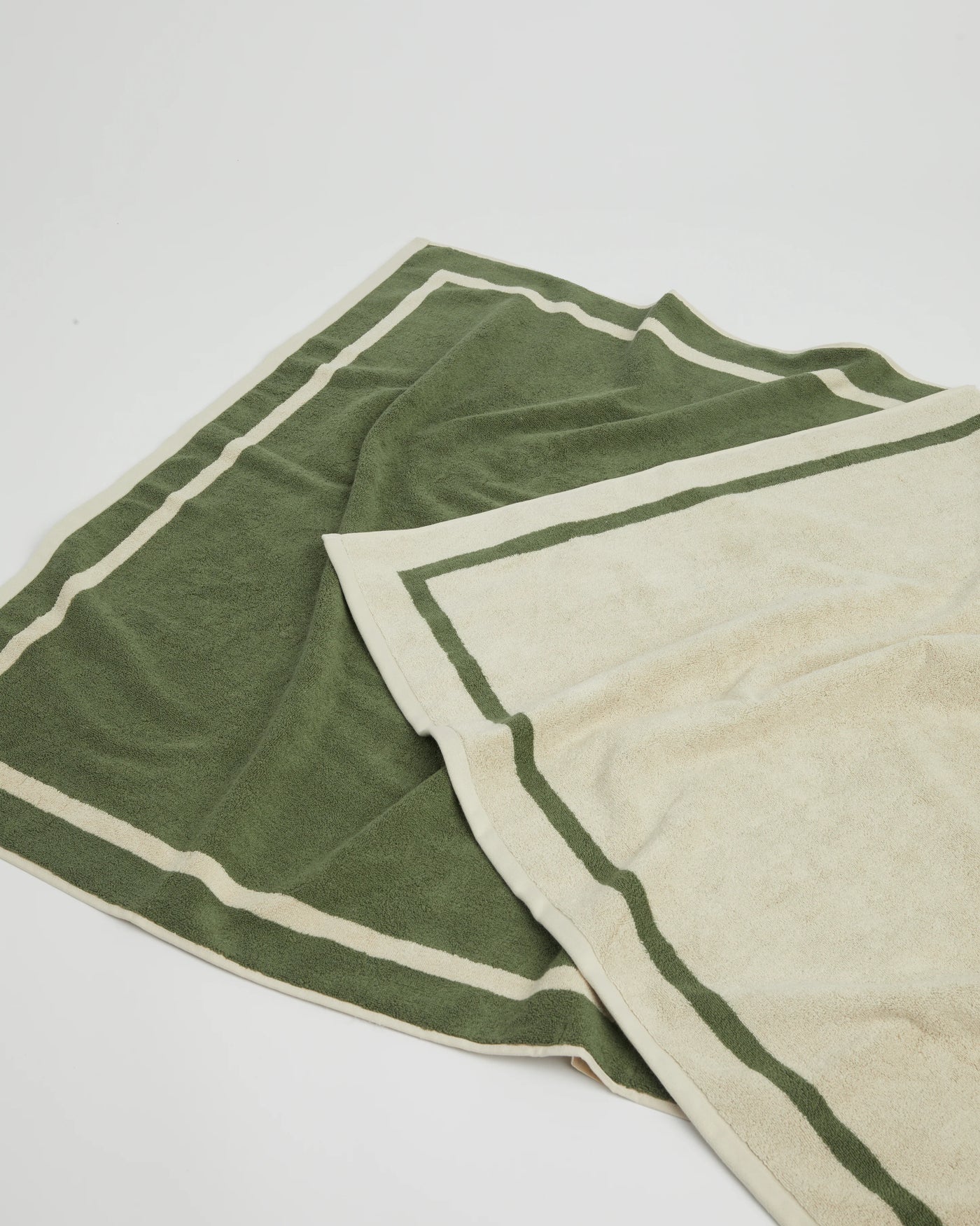 Two folded towels, one green and one beige, on a white background
