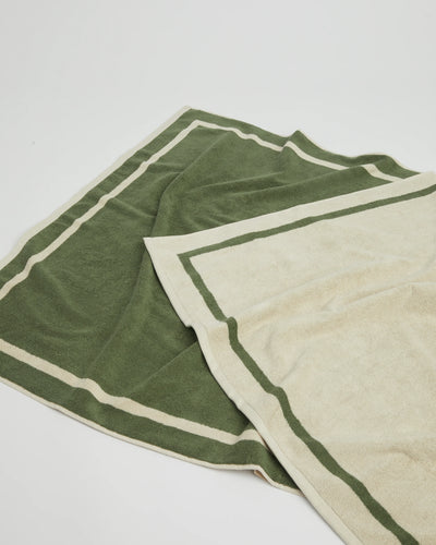 Two folded towels, one green and one beige, on a white background