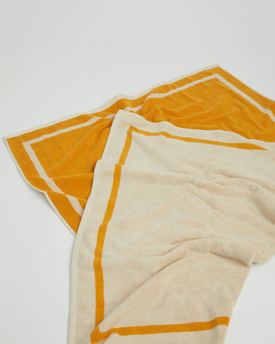 Two towels, one yellow and one beige, on a white background