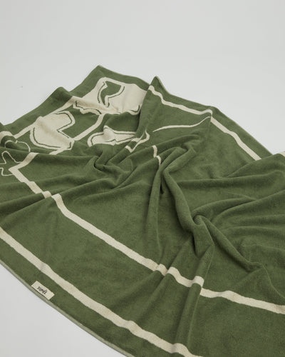 Green towel with white stripes on a light gray background