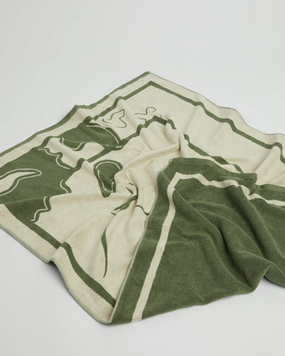 Green and beige towel with abstract design on a light gray background